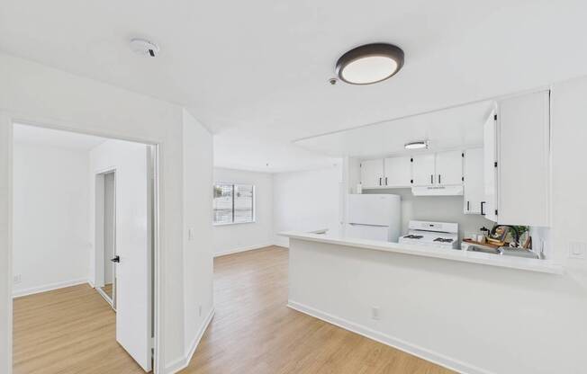 A white kitchen with a white fridge and cupboards.