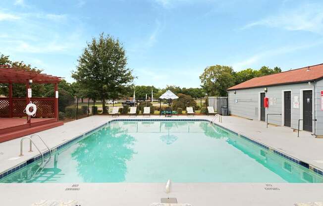 A large indoor pool with a red pergola and trees in the background.