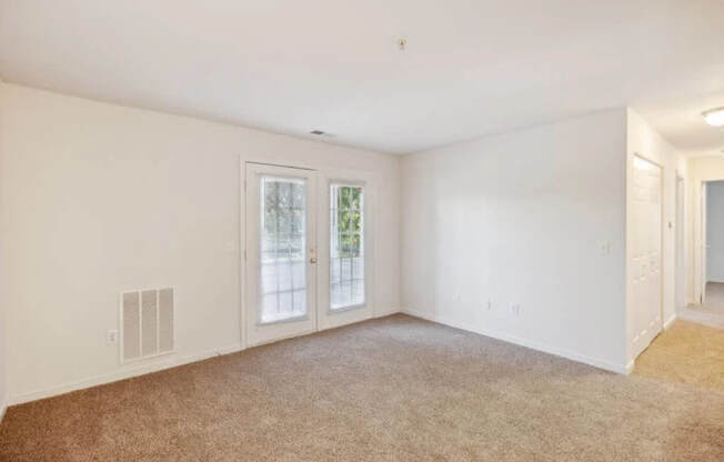 A room with a carpeted floor and a window with a view of trees.