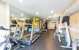 A gym with treadmills, elliptical machines, and exercise balls.