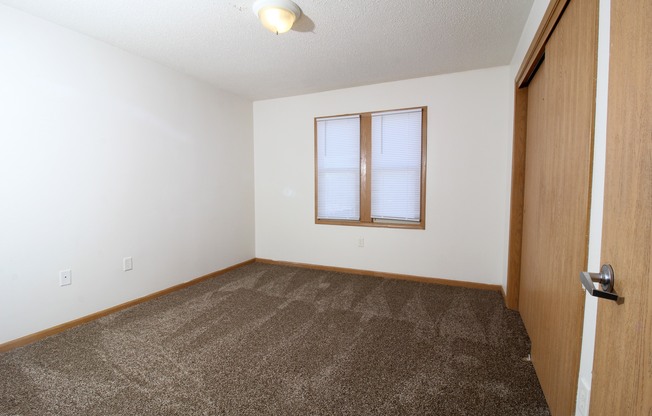 a bedroom with a carpeted floor and a window