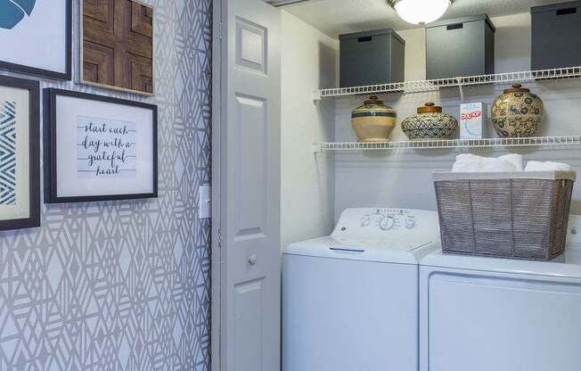 A laundry room with a washer and dryer, a basket, and decorative vases.