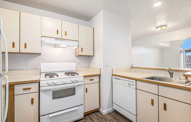 A kitchen with white appliances and wooden cabinets at Brentwood Park Apartments in LaVista, NE