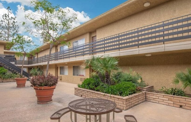 a patio outside of a building with a table and chairs at Villa La Paz Apartments, Bellflower