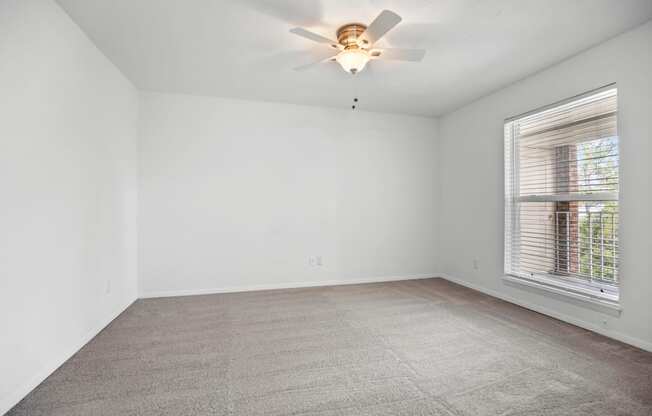 an empty room with a ceiling fan and a window