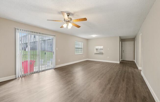 A room with a ceiling fan and sliding glass doors.