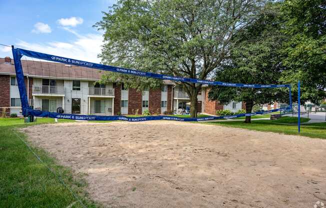 A volleyball net is set up in the sand in front of a brick building.