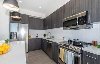 A modern kitchen with a stainless steel refrigerator, oven, and microwave.