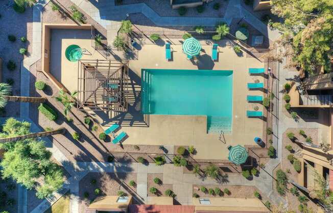 An aerial view of a pool surrounded by trees and a patio area.