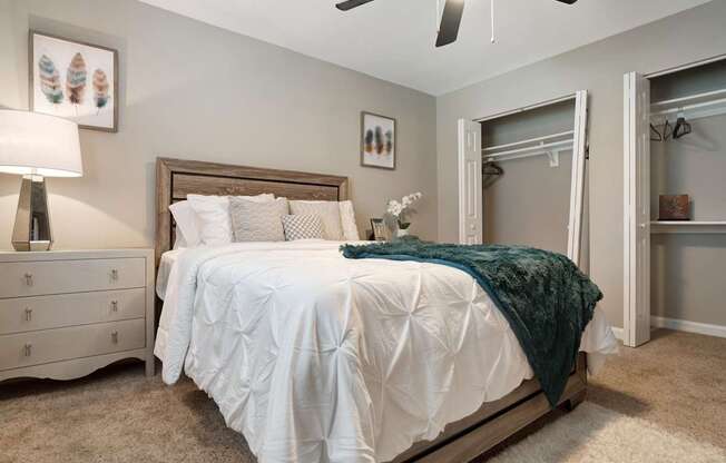 A bedroom with a white bed and a green throw blanket.
