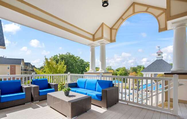 A patio with blue cushions and a white railing.