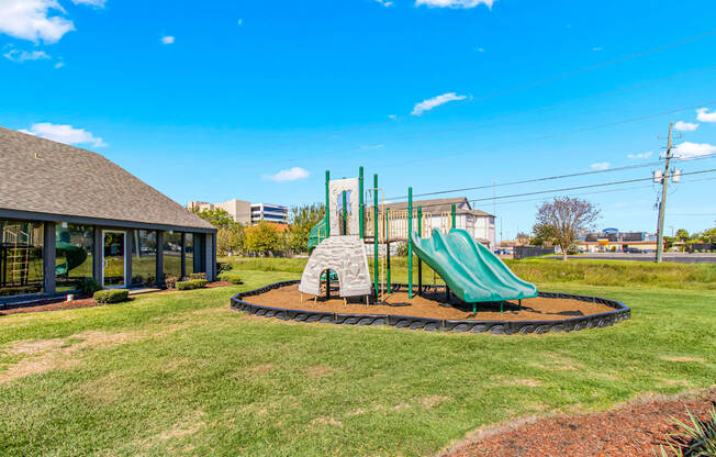 A playground with a green slide and a sandbox.