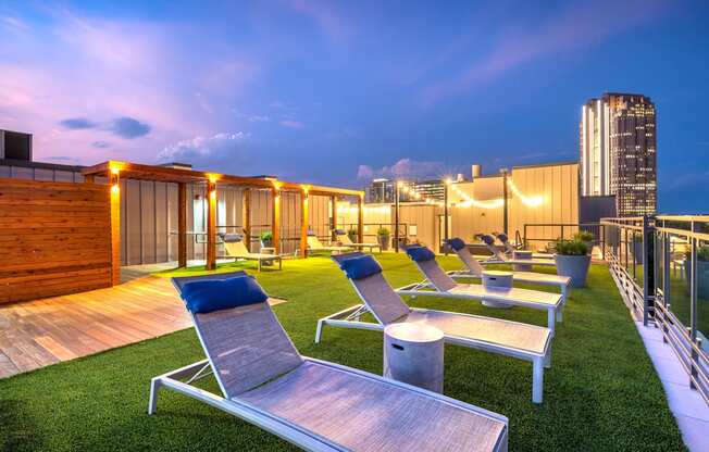 Lounge chairs sitting next to the rooftop pool that faces downtown Dallas