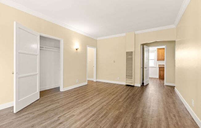 a living room with a hard wood floor and a door to a closet