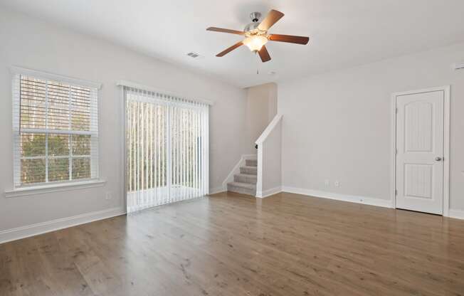 Harris Trail Luxury Townhomes for rent Richmond Hill, GA photo of an empty living room with white walls and a ceiling fan