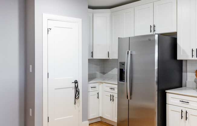 a kitchen with white cabinets and a stainless steel refrigerator