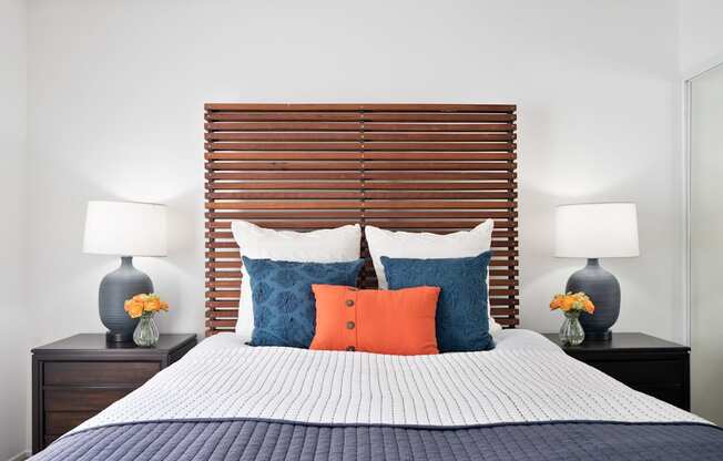 a bedroom with a bed with blue and orange pillows