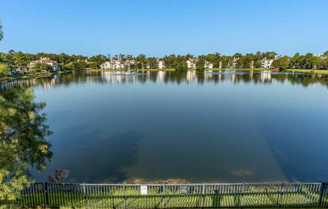 a view of a lake with a fence and houses in the background