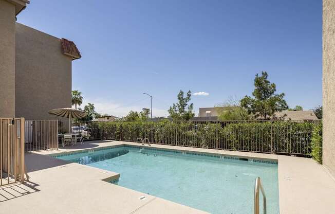 A pool surrounded by a fence and a building.