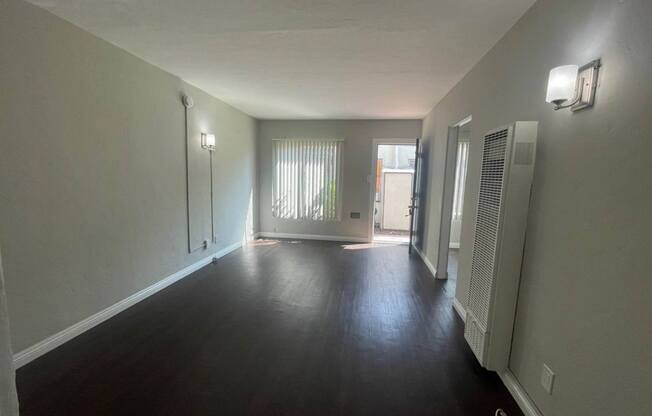 an empty living room with a hard wood floor and white walls