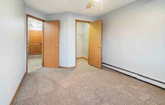 A room with a carpeted floor and two wooden doors.