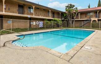 a swimming pool with a fence around it and a building in the background