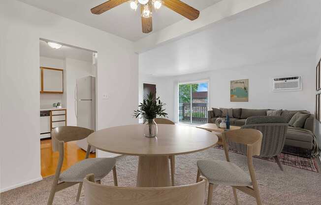 a living room with a ceiling fan and a dining table with four chairs