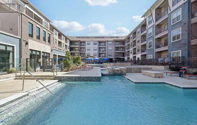 A swimming pool in a residential area surrounded by apartment buildings.