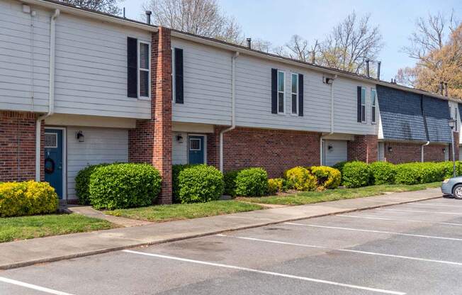 a brick and white building with a parking lot