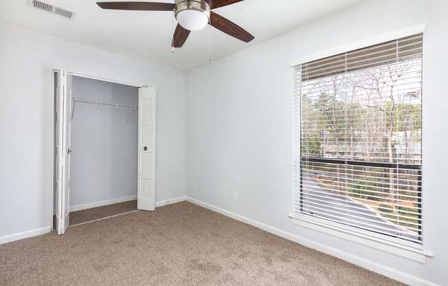 an empty room with a large window and a ceiling fan