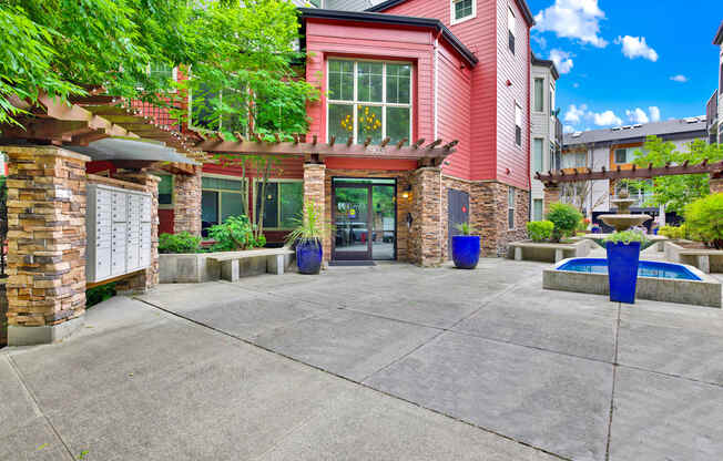A red building with a stone pillar and a tree in front.