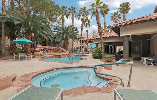 A pool surrounded by palm trees and a patio area.