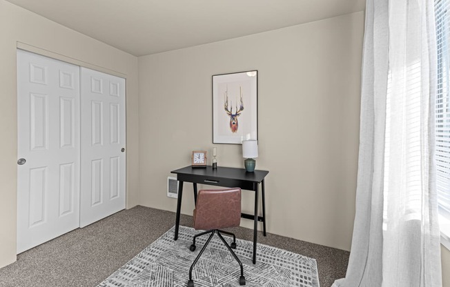 a bedroom with a desk and a chair and a window