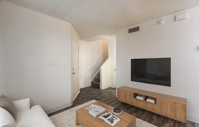A living room with a staircase leading to the second floor.