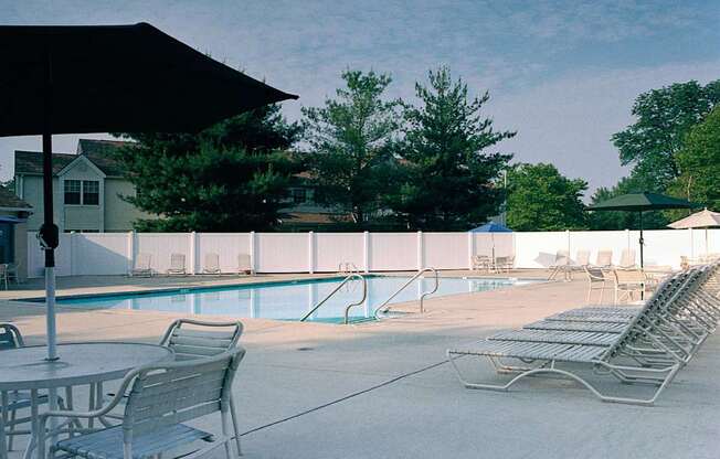 a swimming pool with chairs and tables and an umbrella