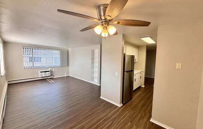 A room with a ceiling fan and wooden flooring.