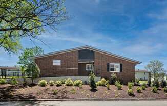 A small brick building with a white signboard on it.