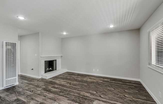 A room with a fireplace and wood flooring.