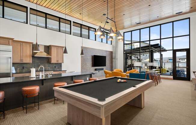 a pool table in a clubhouse with a kitchen and living room