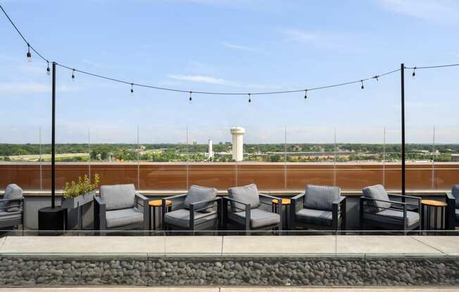 a rooftop patio with chairs and tables and a view of the city