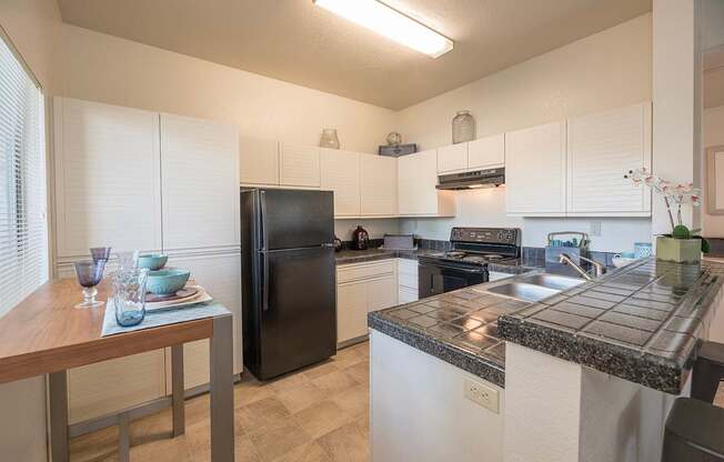 A kitchen with black appliances and white cabinets at Autumn Oaks Apartments, Roseville, CA, 95678