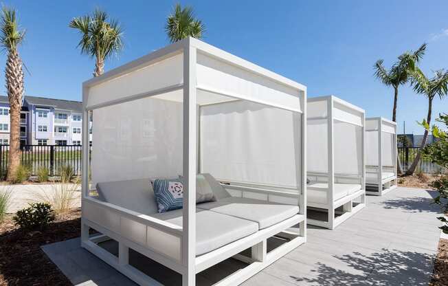 a row of white cabanas on Concorde's pooldeck with palm trees in the background