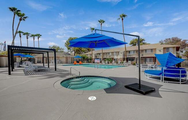 A pool area with a blue umbrella and a hot tub.