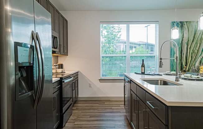 a kitchen with dark cabinets and a large window