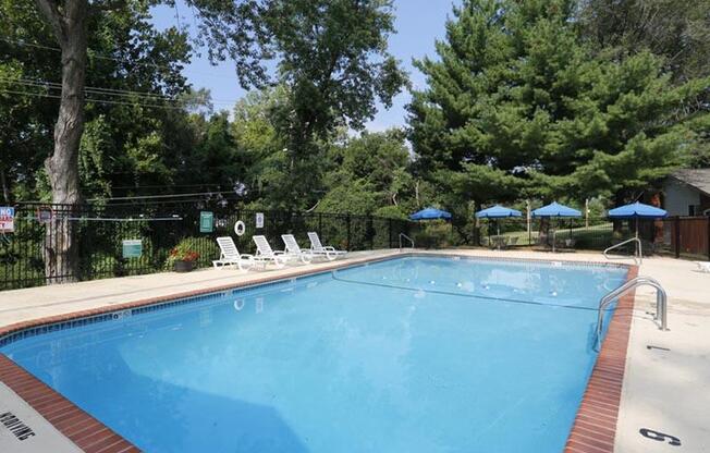 a large swimming pool with lounge chairs and umbrellas