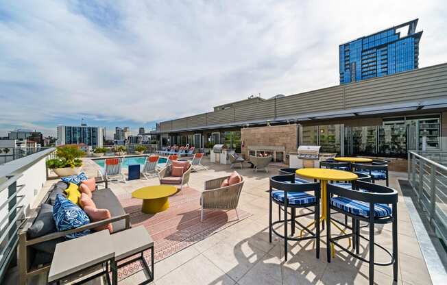 a rooftop patio with tables and chairs and a city in the background