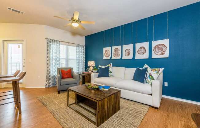 a living room with a white couch and a blue accent wall at Villa Espada Apartments, Texas, 78221