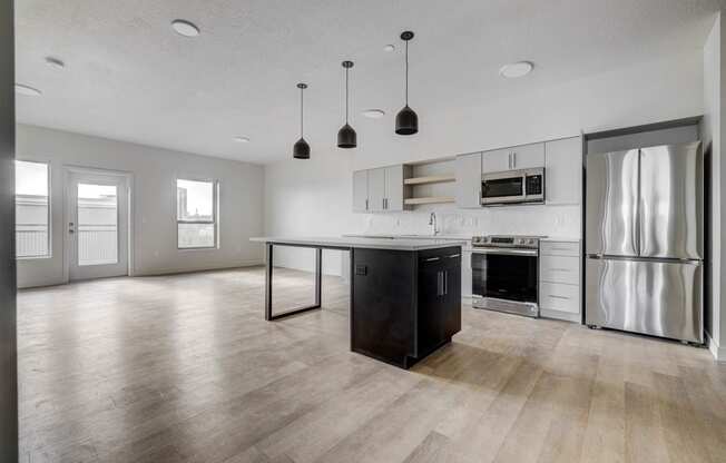 an empty kitchen and living room with stainless steel appliances and a island