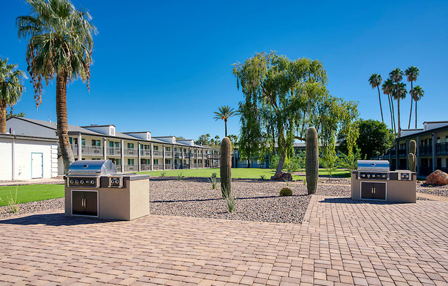 A sunny day at a courtyard with palm trees and a building in the background.