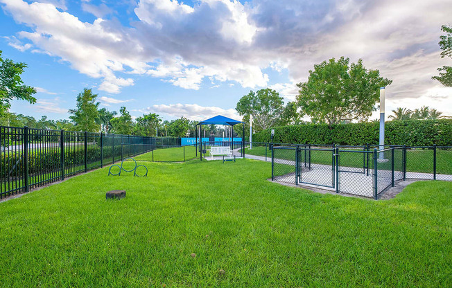 a fenced in dog park with a playground and a gazebo